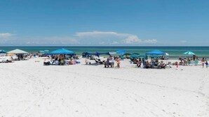 A beach with white sand, blue umbrellas, and people. - Fall in Love with Florida!-Now at Reduced Rates (Santa Rosa Beach)