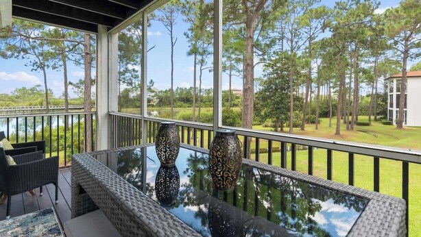 A balcony with wicker furniture and two decorative vases, overlooking a grassy area with trees and a building in the background. - Fall in Love with Florida!-Now at Reduced Rates (Santa Rosa Beach)