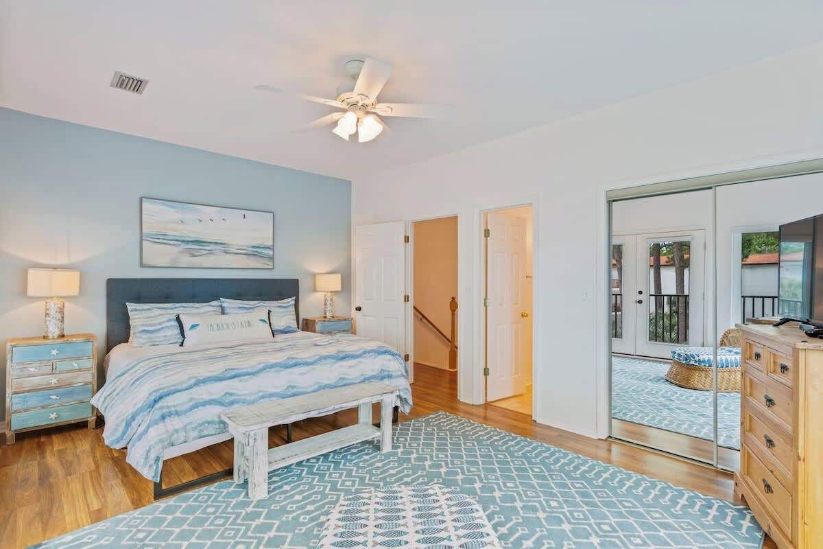 A bedroom with a bed, bedside tables, a ceiling fan, and a view through a glass door to an outdoor area.