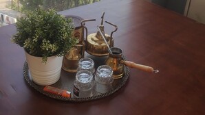 Una mesa con una bandeja de té y una planta en maceta, con vistas a un río, edificios y palmeras.