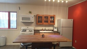 A modern kitchen with a wooden island, white appliances, and a red accent wall.
