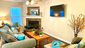 A living room with a fireplace, a television mounted on the wall, and a sofa set.