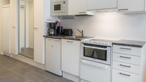 A modern kitchen with white cabinetry, a built-in microwave, a coffee maker, and a stove.