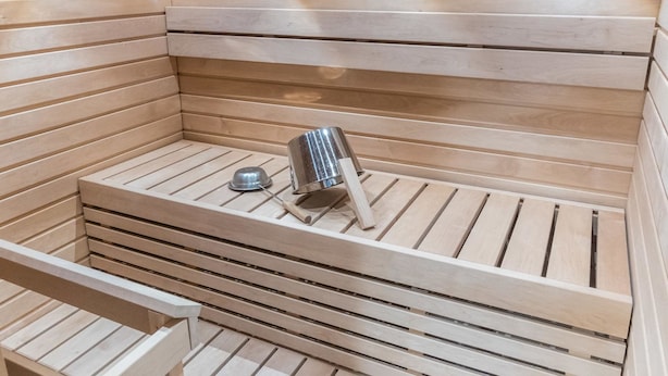 A sauna with wooden benches and a metal heater.