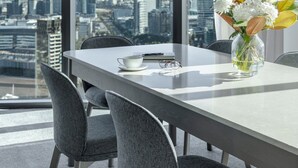 Ein moderner Essbereich mit Blick auf die Stadt, eine Vase mit Blumen und eine Tasse auf dem Tisch.