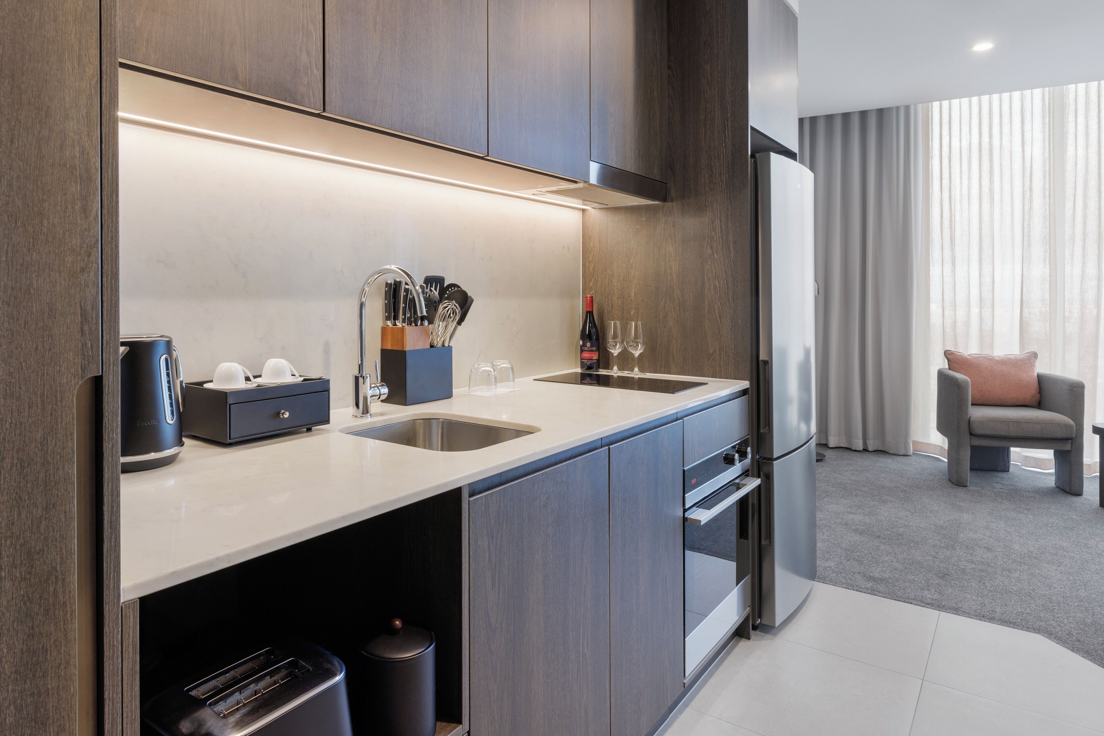 A modern kitchen with a built-in oven, a coffee maker, and a wine bottle.