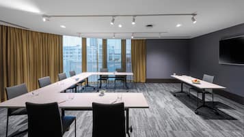 Ein Konferenzraum mit einem langen Tisch, Stühlen und einem großen Fenster mit Vorhängen.