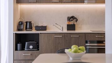 A modern kitchen with wooden cabinets, a countertop, a kettle, a toaster, and a bowl of apples.