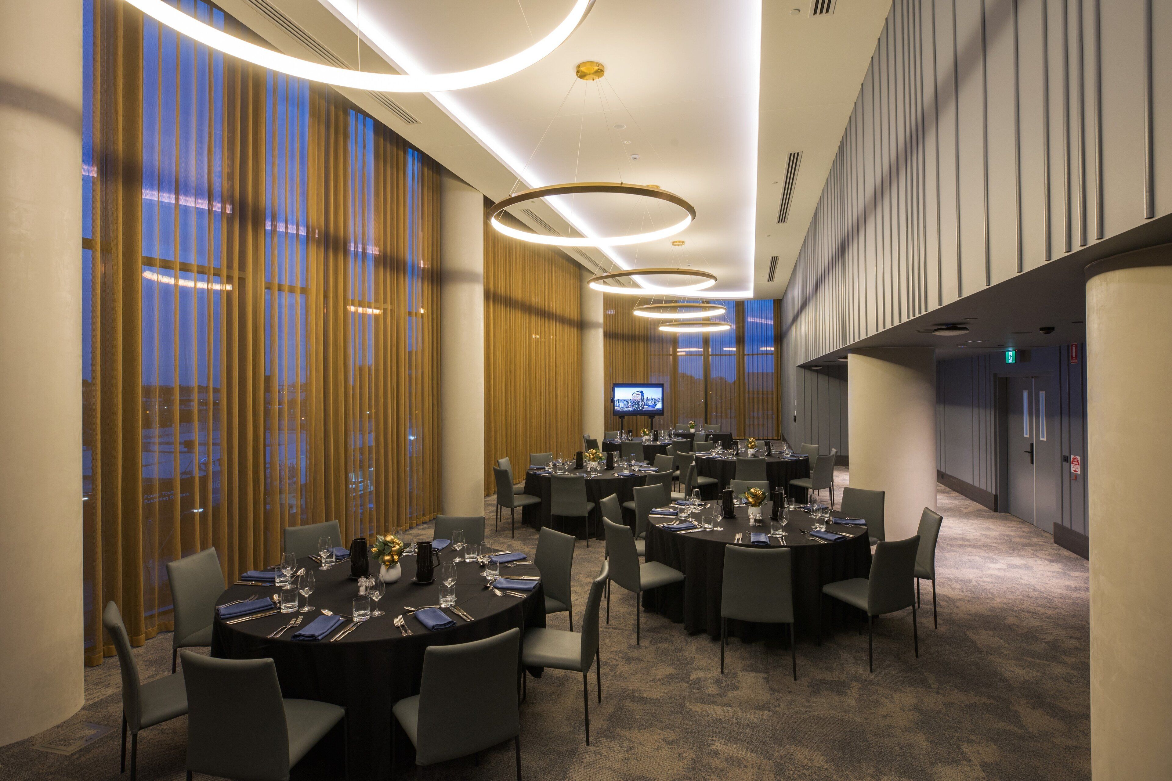 A conference room with multiple tables, chairs, and a television screen.
