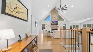 A spacious living area with a wooden floor, a high ceiling, and a fireplace. - Lakeview Home/Private Boat Dock/Hot tub/Golf Cart/Gameroom/Stunning Fall Views (LaFollette)