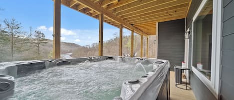 Ein Whirlpoolbereich mit Holzbalken und Blick auf Bäume und Hügel.