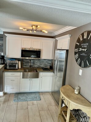 Una cocina moderna con armarios blancos, electrodomésticos de acero inoxidable y un reloj de pared grande.