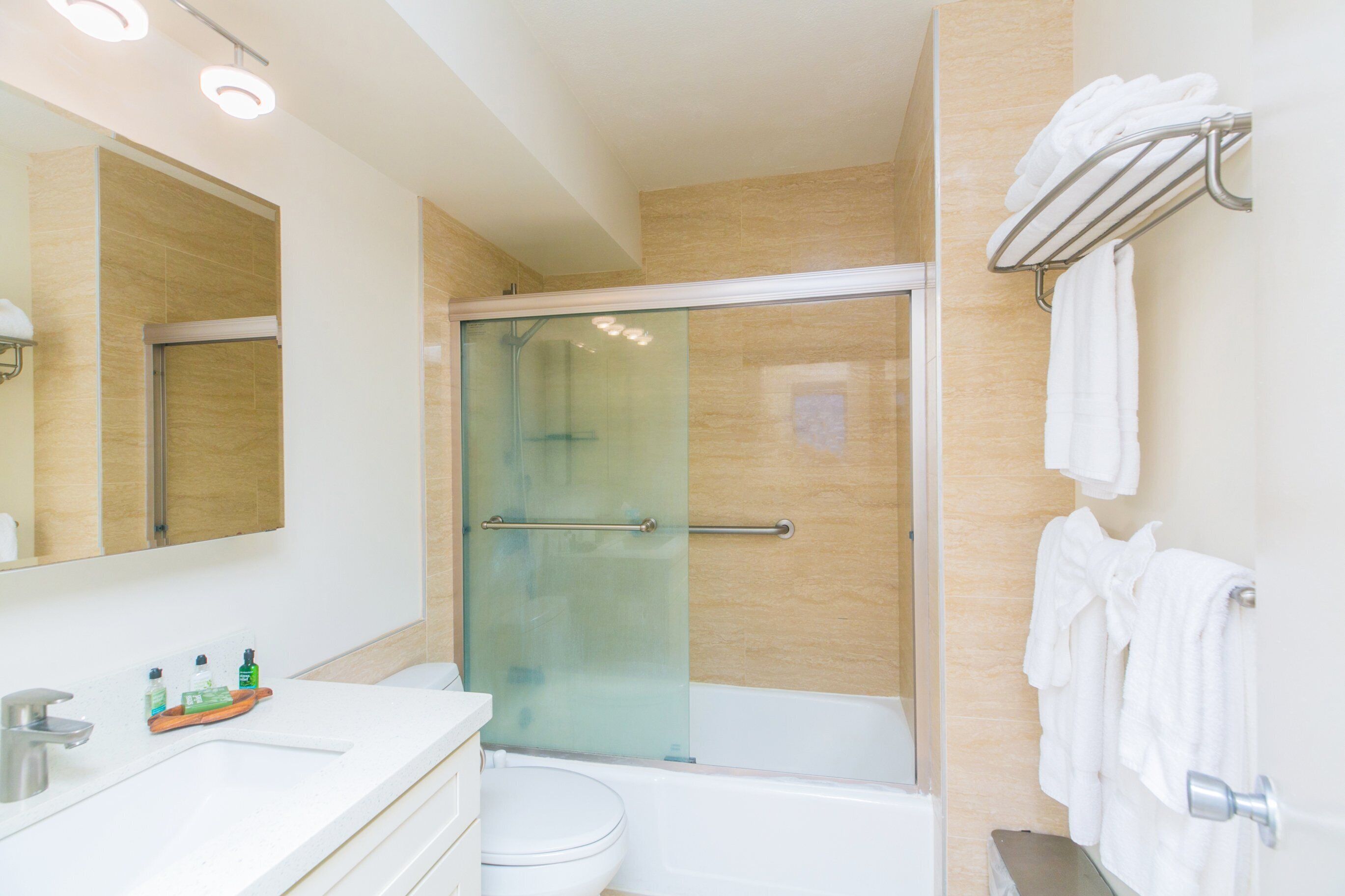 A modern bathroom with a glass-enclosed shower, a white sink, and a towel rack.