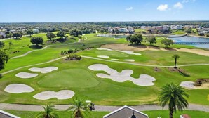 A golf course with bunkers, a bridge, and a body of water. - Private Pool | Reunion Membership | 8 Miles to Disney (Kissimmee)