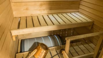 A sauna with wooden benches and a metal container.