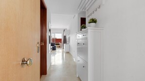 A hallway with a wooden door, white cabinets, and a potted plant. - Apartment Sleeps 6 with Pool (Fuengirola)