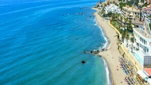 A coastal cityscape with a beach, buildings, and clear blue waters.