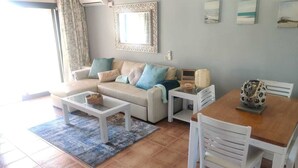 A living room with a sofa, coffee table, and dining table.