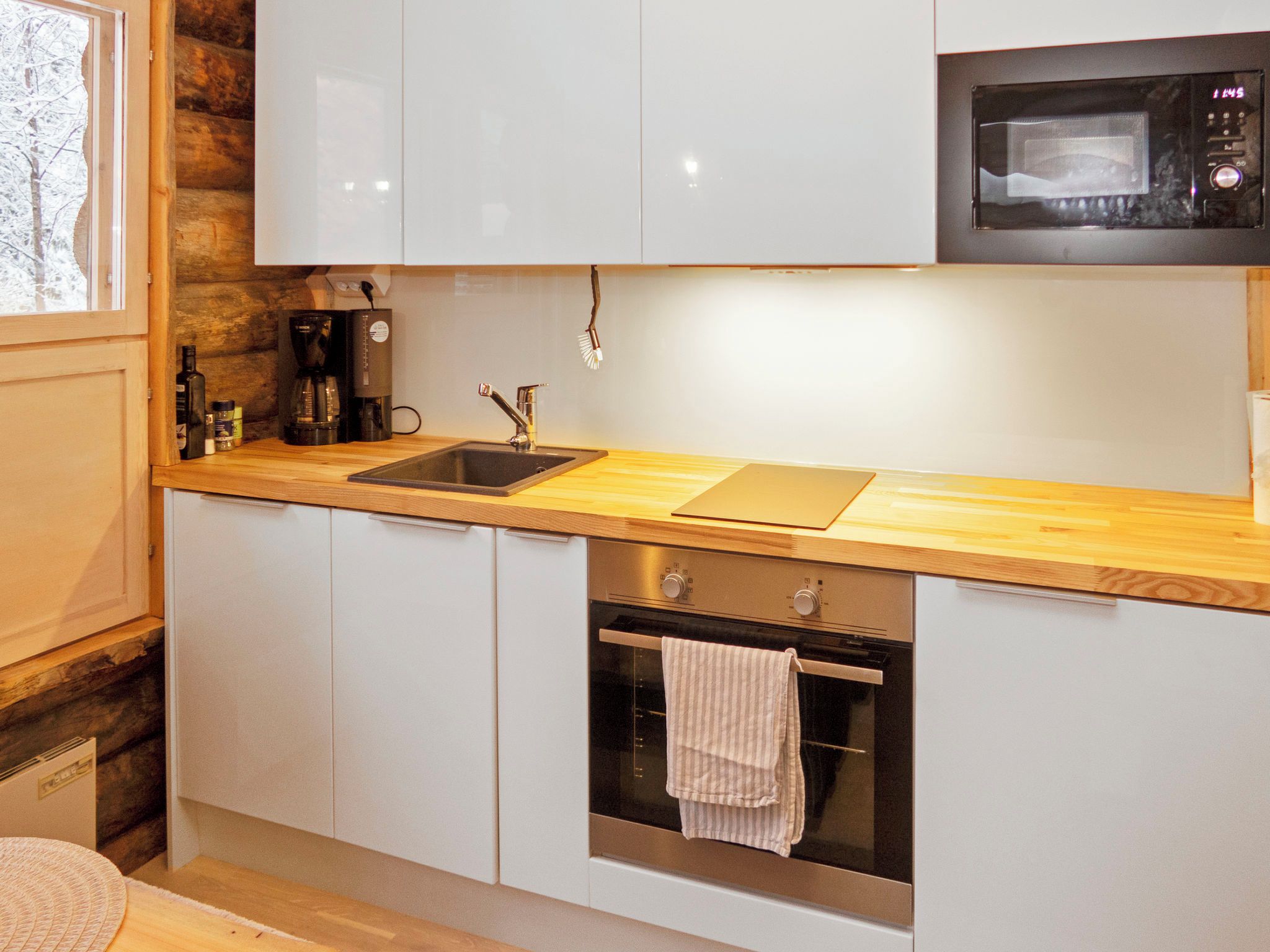 A modern kitchen with a wooden countertop, stainless steel appliances, and a built-in oven.