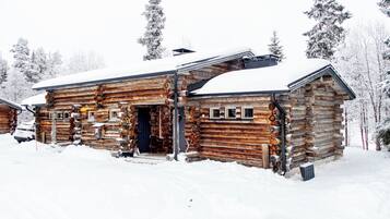 A log cabin with a snow-covered roof, a front door, and a chimney.