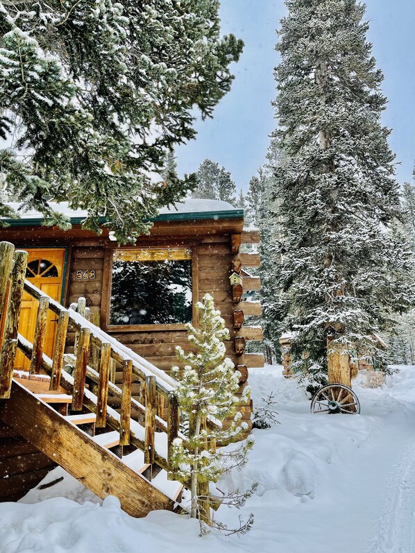 A wooden cabin with a wooden staircase leading to a door marked "563".