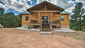 A wooden cabin with a porch, a staircase leading to the entrance, and a gravel driveway. - Cripple Creek Mountain Getaway w/ Hot Tub & Views! (Cripple Creek)