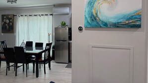 A dining area with a table and chairs, a refrigerator, and a painting on the wall.