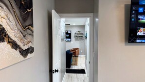 A hallway leading to a living room with a TV mounted on the wall displaying a sports channel.