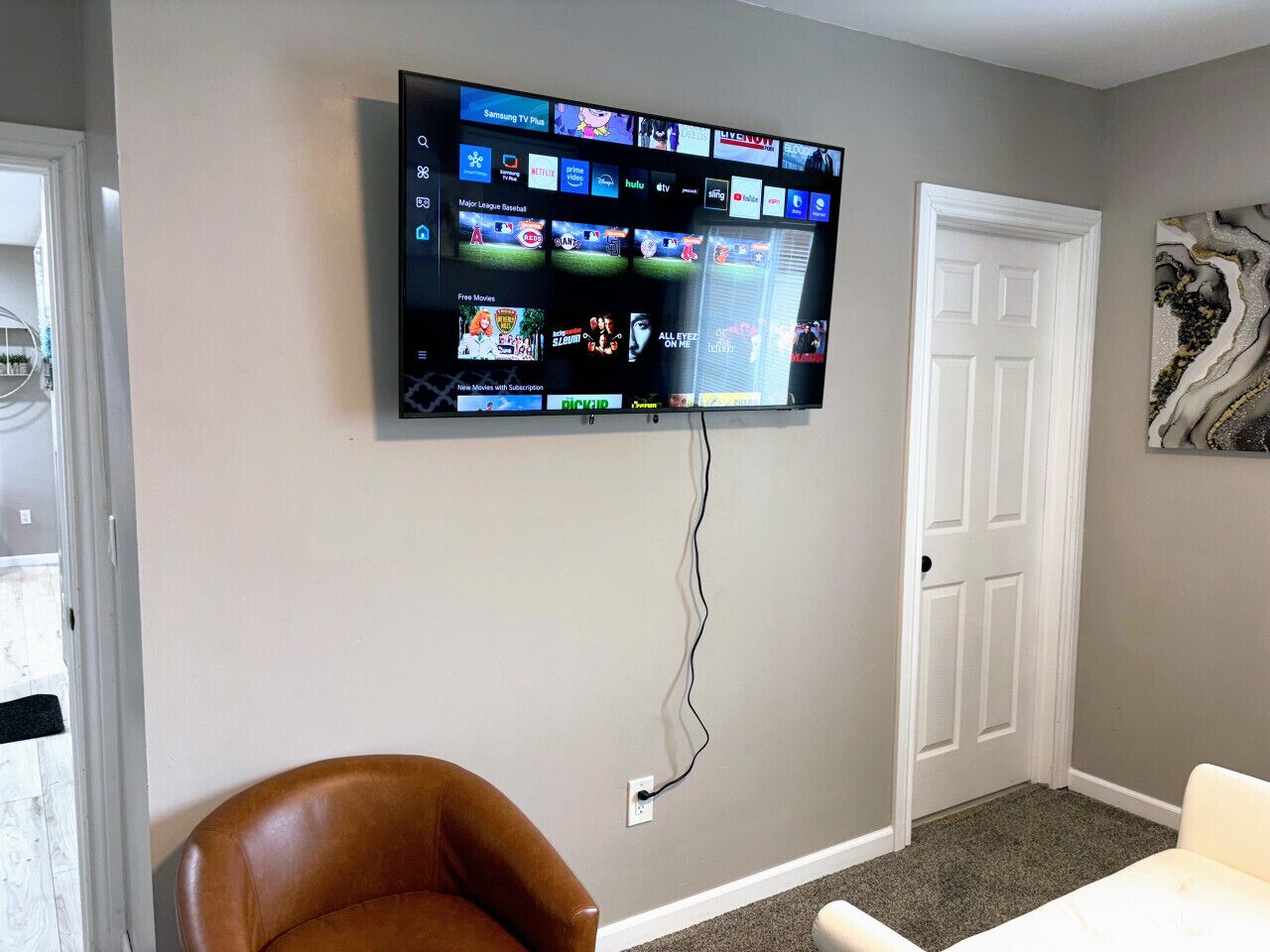 Ein Wohnzimmer mit einem an der Wand befestigten Flachbildfernseher, der verschiedene Streaming-Dienste anzeigt.