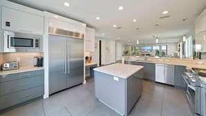 A modern kitchen with stainless steel appliances, a marble countertop, and a central island. - White Pearl - Modern Vacation Rental House in Destiny by the Sea with Shared Pool (Destin)