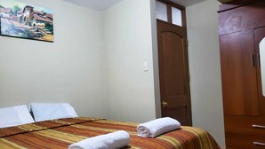 Een hotelkamer met een bed, een houten kledingkast en een schilderij aan de muur.