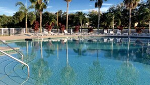 Une piscine aux eaux cristallines, dotée de chaises longues et entourée d’une clôture blanche.