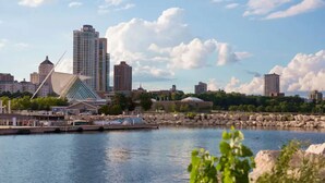 A cityscape with modern buildings, a waterfront, and a distinctive architectural structure.