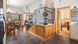 A spacious kitchen with a dining area, a wooden staircase, and a view of the outdoors. - Relaxing Walk-in Cabin in Branson Theatre District, Golf and Ticket Discounts (Branson)