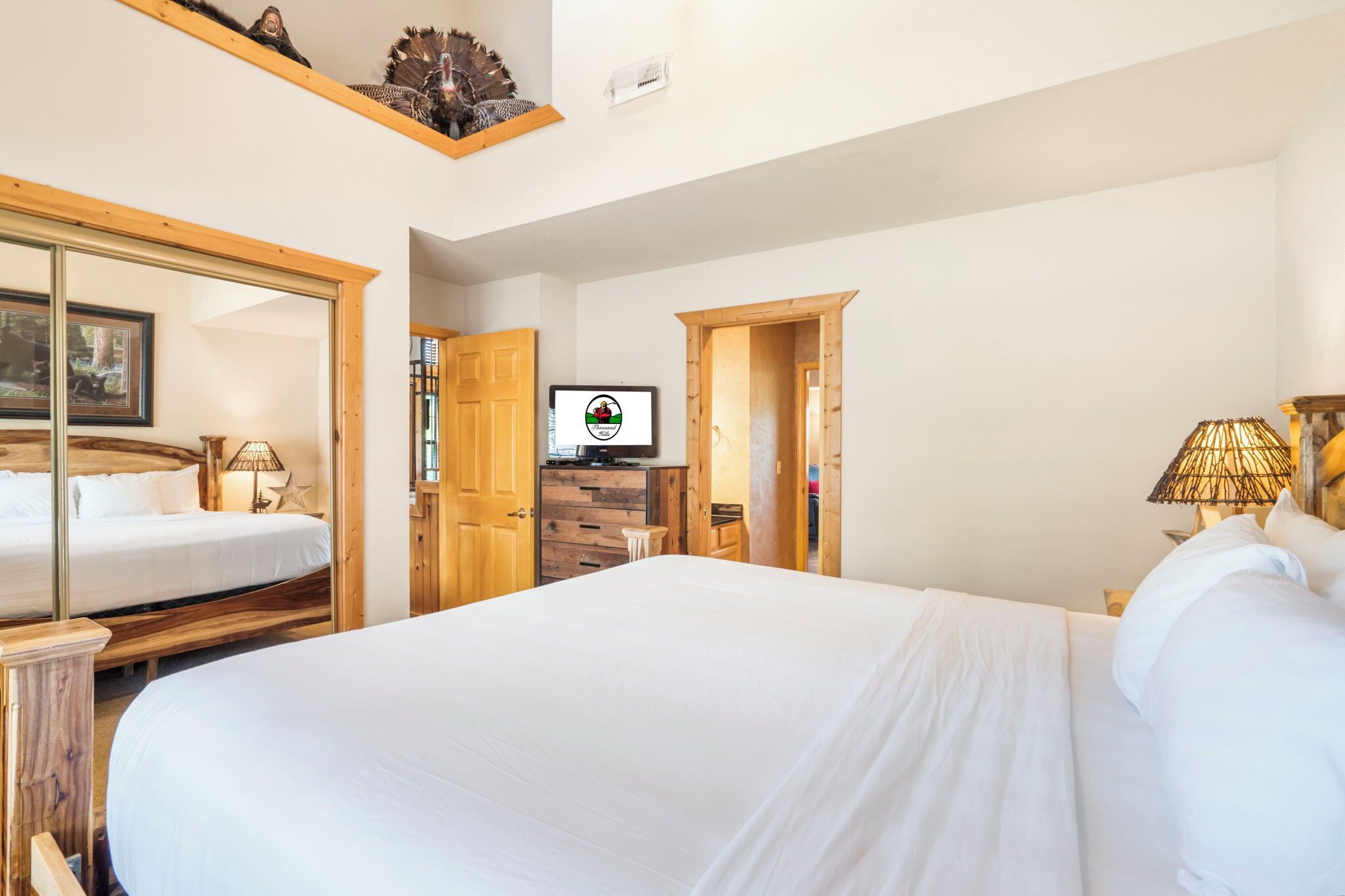 Hotellihuone, jossa on suuri sänky, puiset huonekalut, televisio ja työpöytä.