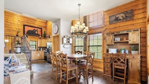 A rustic cabin interior with a dining area, wooden cabinets, and a chandelier. - Relaxing Walk-in Cabin in Branson Theatre District, Golf and Ticket Discounts (Branson)
