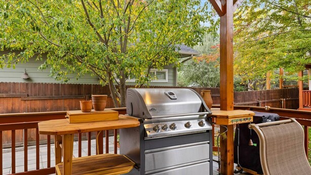 An outdoor grill setup with a wooden table, a bench, and a covered area. - The REAL BOISE RETREAT! AMAZING LOCATION & STELLAR Backyard. Bring your DOG! 2 mins to Downtown! (Boise)