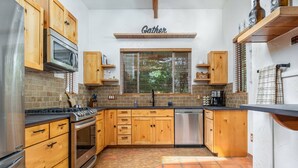 A kitchen with wooden cabinets, a stainless steel refrigerator, a microwave, and a stove. - The REAL BOISE RETREAT! AMAZING LOCATION & STELLAR Backyard. Bring your DOG! 2 mins to Downtown! (Boise)