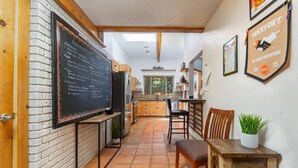 A kitchen with a chalkboard menu, wooden cabinets, and a dining area with a table and chairs. - The REAL BOISE RETREAT! AMAZING LOCATION & STELLAR Backyard. Bring your DOG! 2 mins to Downtown! (Boise)