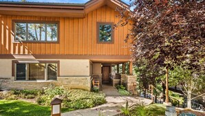 Une maison à deux étages, avec des fondations en pierre, un revêtement extérieur en bois et un jardin aménagé à l’avant, avec un chemin menant à l’entrée.