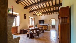 Un vaste espace dédié à la salle à manger, avec une grande table en bois, des éléments décoratifs en pierre et un plafond rustique.