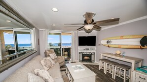 Un salon avec un canapé, une cheminée, un téléviseur et une planche de surf accrochée au mur.