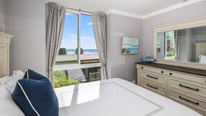 Une chambre avec un grand lit, une commode, un miroir et une vue sur la plage.