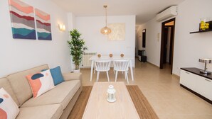 A modern living room with a sofa, a coffee table, and a dining area with a table and chairs. - Apartment Drac Blanc 1-4 close to the Beach with Sea View, Pool, Terrace & Wi-Fi (CALA RATJADA)