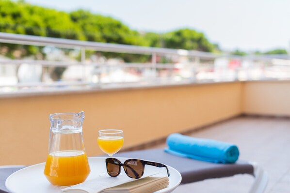 A table with a pitcher of orange juice, a glass of orange juice, and sunglasses on a white plate.