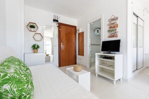 Un dormitorio con cama, televisor en un mueble, una puerta y una pared decorada con letreros motivacionales.