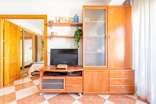 A room with a wooden cabinet, a television, and a bed.