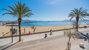 A beachside promenade with palm trees, a playground, and a view of the sea. - Stunning Apartment "Cana Ferrera" with Sea and Mountain Views, Balcony, A/C & Wi-Fi (Puerto de Pollensa)