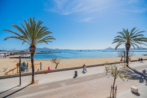 Eine Strandpromenade mit Palmen, einem Spielplatz und Blick aufs Meer.