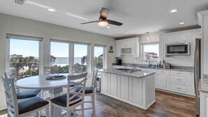 A modern kitchen with white cabinets, a large island, and a view of the ocean. - Salt Therapy N - Coastal escape w/ beach access (St Augustine)